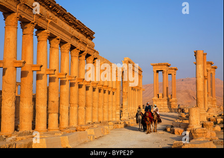 Touristen, Kamelreiten entlang der Colonnaded Straße, Palmyra, Syrien Stockfoto