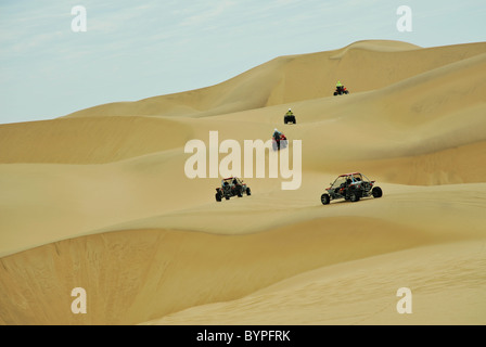 Konvoi von Quad Bikes und Dune Buggys Reiten auf gelben Sanddünen auf ATV Abenteuer in der Wüste Tour Swakopmund Namibia Landschaften Stockfoto