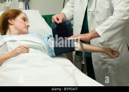 Arzt die Blutdruckmanschette am Patienten im Krankenhaus Stockfoto