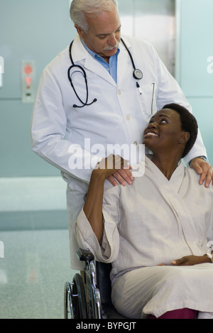 Arzt beruhigend Patientin im Rollstuhl Stockfoto