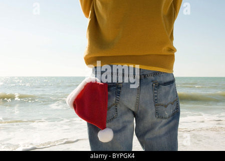Mann am Strand betrachten, Weihnachtsmütze auf der Rückseite Tasche Stockfoto