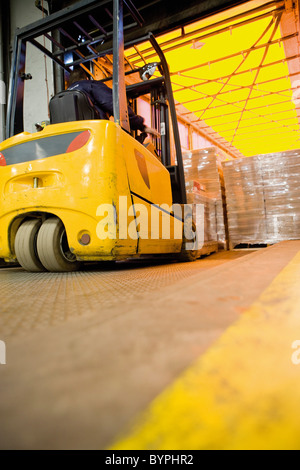 Gabelstaplerfahrer laden eingehülltes Lager Paletten mit Kartons auf Anhänger Stockfoto