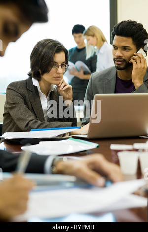 Führungskräfte arbeiten zusammen, einer mittels Handy Stockfoto