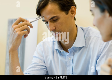 Mann in Gedanken, blickte mit Stift gegen Stirn Stockfoto