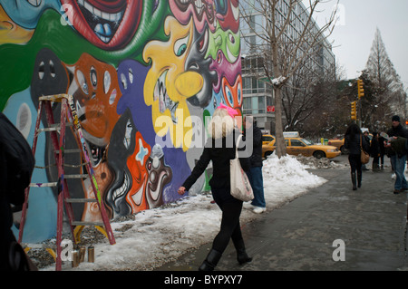 Ein Fußgänger Spaziergänge durch ein Wandbild des Künstlers Kenny Scharf an der Ecke Bowery und Houston Street in New York Stockfoto