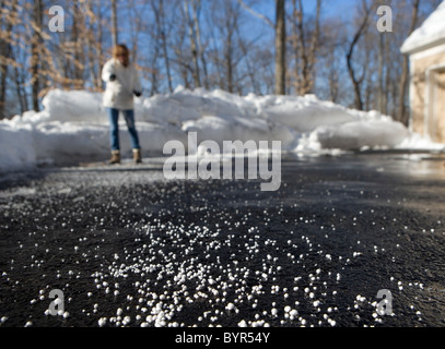 Eine Frau werfen Salz auf einer Einfahrt zum Schmelzen von Eis und Schnee Stockfoto