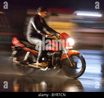 Indien, Uttar Pradesh, Agra Mensch auf Motorrad ohne Helm in der Nacht im Monsun-Regen Stockfoto