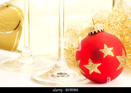Nahaufnahme von einem roten stumpf Weihnachtskugel mit Champagner Glasboden vor eine Flasche Champagner Stockfoto