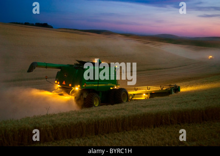 Landwirtschaft - John Deere Mähdrescher erntet Weizen in der Abenddämmerung in der Palouse Region / in der Nähe von Pullman, Washington, USA.