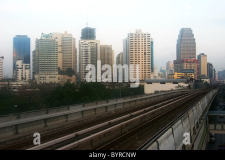 Gebäude sind im frühen Morgennebel gehüllt und Hochbahn Bahnen sind leer an einem frühen Morgen in Bangkok, Thailand. Stockfoto