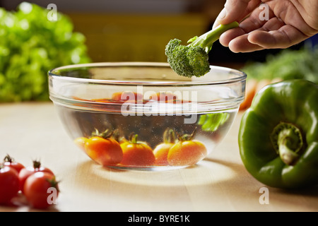 rote Tomaten und Brokkoli in Schüssel mit Wasser, mit Paprika und anderes Gemüse auf Küchentisch gewaschen. Horizontale Form Stockfoto