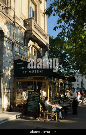 Ein Mann saß in der Sonne vor einem Café in Paris, Frankreich Stockfoto