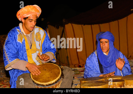 Blau Berber und Tuareg Männer spielen Djembe bongo Trommeln in der Nacht im Erg Chebbi wüste Marokko Stockfoto