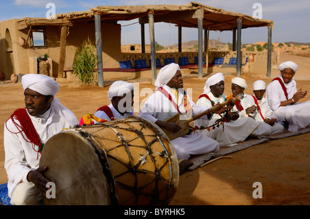 Gnawa-Musiker im weißen Djellabas und Turbane singen und spielen afrikanischen Musik während der Sitzung in der Wüste Straße von Khemliya Dorf Marokko Stockfoto