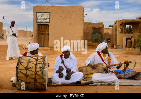 Gnawa-Musik-Gruppe in weißen Turbanen und Djellabahs sitzen und spielen Musik in Khemliya Wüste Dorf Marokko Nordafrika Stockfoto