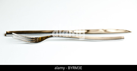 Messer und Gabel aus modernen rostfreien Stahl Design isoliert gegen weiße und reflektierenden golden hellbraun Stockfoto