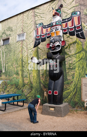 Ein Junge liest die Plakette auf einem Totempfahl in Duncan, BC, Kanada.  Duncan ist die Stadt des Totems bezeichnet. Stockfoto