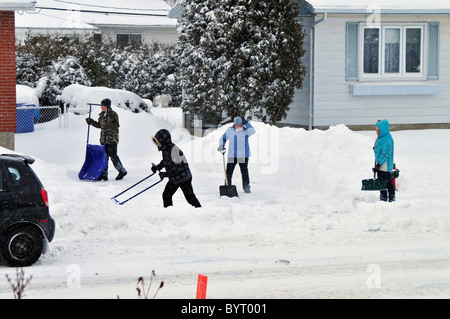 Nach einem Schneesturm sehen Menschen ihre Einfahrten und Höfe in Quebec, Kanada den Schnee entfernen. Stockfoto