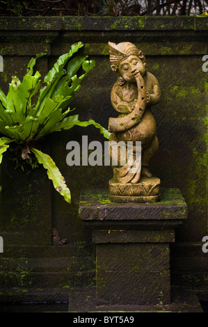 Eine schöne steinerne Skulptur ein Flötenspieler ziert eine Wand in Ubud, Bali, Indonesien. Stockfoto