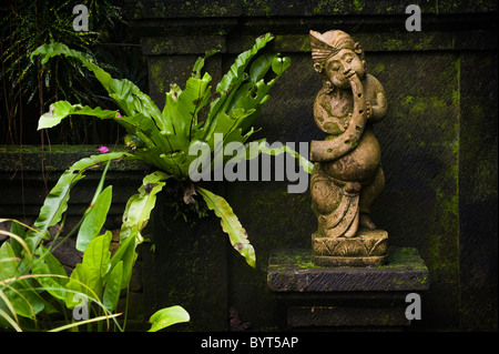 Eine schöne steinerne Skulptur ein Flötenspieler ziert eine Wand in Ubud, Bali, Indonesien. Stockfoto