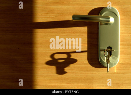 Schlüssel im Türschloss wirft einen langen Schatten Stockfoto