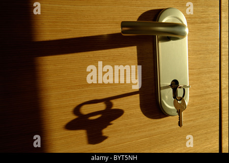 Schlüssel im Türschloss wirft einen langen Schatten Stockfoto