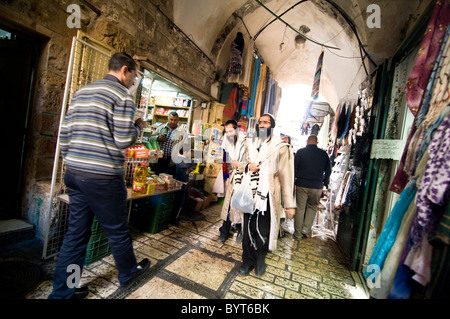 Orthodoxe jüdische Männer zu Fuß durch die lebhaften Märkte der muslimischen Viertel in der Altstadt von Jerusalem. Stockfoto