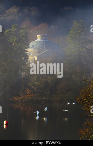 Belle Isle Rundhaus mit Schwäne fliegen vorbei an nebligen Tag im See widerspiegelt Stockfoto