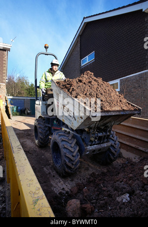 Muldenkipper Entleerung seine Schaufel voll Erde in ein überspringen Stockfoto