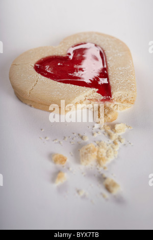 Foto von herzförmige Kekse gefüllt mit roter Marmelade auf einem weißen Hintergrund. Enthält gebrochen Keks und Krümel. Valentinstag-Konzept. Stockfoto