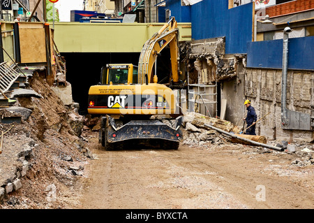 Ein Caterpillar Bagger Baggern, Stein und Erde zum Tunnel unter einer Brücke in Mannerheimintie, Helsinki Stockfoto