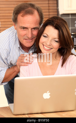 Älteres Paar mit einem Laptop am Küchentisch Stockfoto