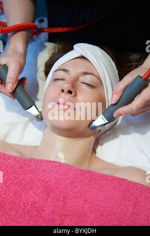 Frau, die eine anregende Gesichtsbehandlung von einem Therapeuten Stockfoto