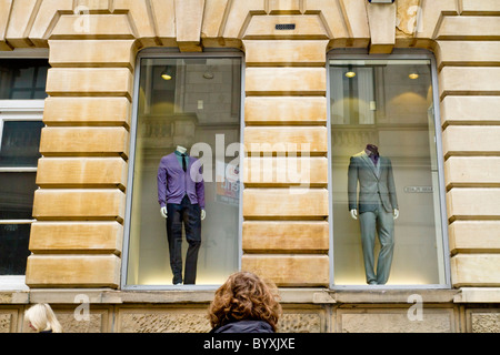 Humorvoller Blick auf zwei kopflose Schaufensterpuppen in einem Schaufenster Anzeige und die Köpfe von zwei Menschen, England, Großbritannien Stockfoto