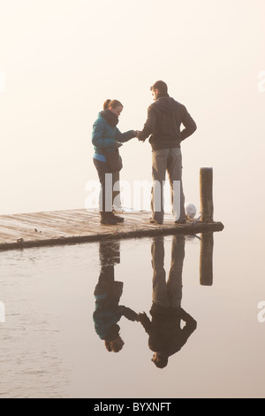 Ein paar auf einem Steg am Waterhead in Ambleside am Lake Windermere, Lake District, Großbritannien. Stockfoto