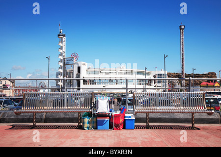 Gepäcktaschen und Picknick allein durch Bänke am Südstrand Blackpool promenade mit Pleasure Beach im Hintergrund Sommertag Stockfoto