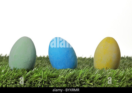 Drei bunte Ostereier auf dem grünen Rasen mit weißem Hintergrund. Stockfoto