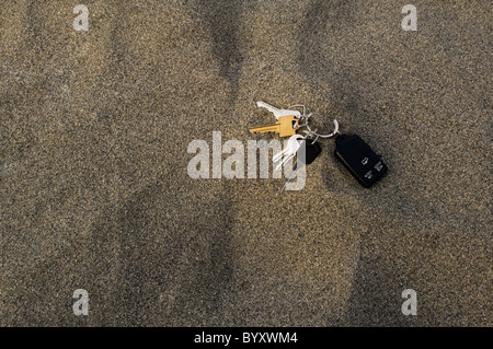 Haus und Auto Schlüssel auf einem Ring mit einer Fernbedienung verloren FOB in den Sand. Stockfoto