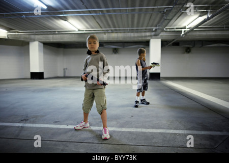 Kinder mit Strumpf Masken und Spielzeugwaffen in Tiefgarage vorzubereiten für große Bankraub. Stockfoto