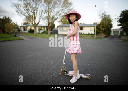 In meiner Straße. Mädchen reitet Roller am Ende des Culdesac, Neuseeland. Stockfoto