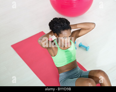 junge afrikanische amerikanische Frau in der grünen Sportswear Bauchmuskeln auf Pad im Fitness-Studio trainieren. Stockfoto