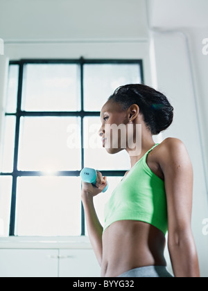 junge afrikanische amerikanische Frau in der grünen Sportswear Krafttraining im Fitness-Club zu tun. Vertikale Form, Seitenansicht, Textfreiraum Stockfoto