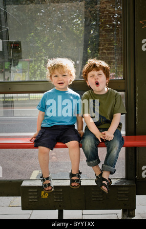 Zwei Brüder sitzt an einer Bushaltestelle. Stockfoto