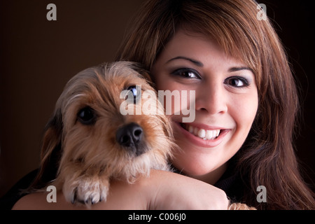 Eine junge Frau in ihrem 20 s hält eine süßen Mischling Beagle Yorkshire-Terrier (auch bekannt als Borkie) Hund. Stockfoto