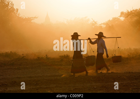 Frauen in ländlichen Gebieten tragen Körbe bei Sonnenuntergang, Bagan (Pagan), Myanmar (Burma) Stockfoto