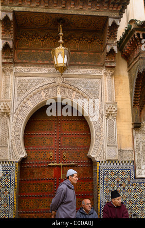 Männer warten auf die reich verzierten Tür Sidi Ahmed Tijani Mosque mit komplizierten Steinbildhauen in Fes el Bali Medina Fes Marokko Nordafrika Stockfoto