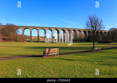 Holzbank im Wasser-Meadows-Park mit Blick auf die Eisenbahn-Viadukt, Penistone, South Yorkshire, England, UK. Stockfoto