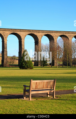 Holzbank im Wasser-Meadows-Park mit Blick auf die Eisenbahn-Viadukt, Penistone, South Yorkshire, England, UK. Stockfoto