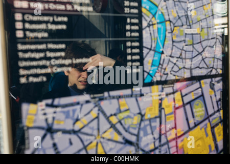 Ein Besucher untersucht eines der vielen Straßenkarten und Stadtpläne von London, dieser befindet sich außerhalb der Holborn Station. Stockfoto