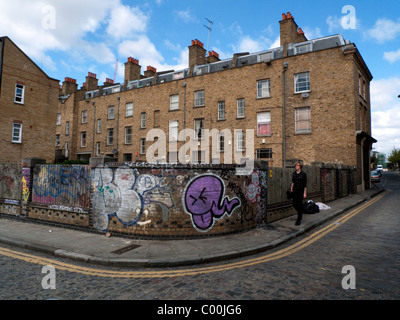 Ein junger Mann in schwarz zu Fuß auf der Rückseite eine Reihe Reihenhäuser auf Grimsby Street in der Nähe von Brick Lane, East End, London England UK KATHY DEWITT Stockfoto